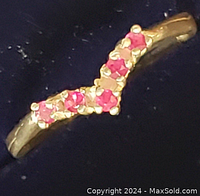 Close-up view of the front of the sterling silver ring showing five round red rubies set in prong settings on a curved band.