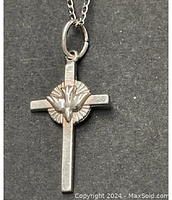 Close-up photo of a 925 sterling silver cross pendant featuring a dove of peace centered on a sunburst background, attached to a silver chain.