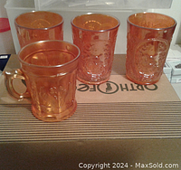 The full set of four carnival glass items including three glasses with windmill motif and one cup with handle and singing bird motif.