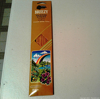 Front of the orange Breezy incense sticks box showing floral design, rainbow, and window displaying incense sticks.