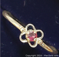 Close-up photo of the ring front showing the four leaf clover design and central ruby gemstone.