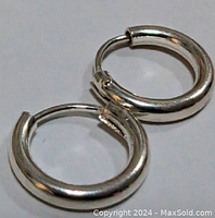 Pair of small sterling silver hoop earrings, closed position, showing polished surface and rounded shape.