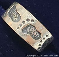 Close-up of sterling silver toe ring showing embossed footprints and toe prints.