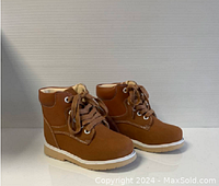 Side angle showing the profile and design of the tan ankle shoes with laces and white sole.