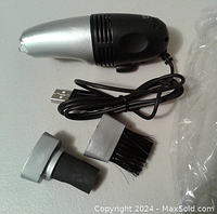 USB mini vacuum cleaner and two attachments with USB cable visible