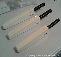 Three Wiltshire Stay Sharp utensils with protective white sheaths and black handles, placed on a countertop.