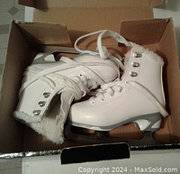 Pair of white youth girls ice skates inside a cardboard box showing fleece lining and metal eyelets for laces