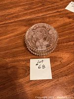 Closed glass candy dish with silver plated lid, showing floral etched design on top and beaded edge on base.