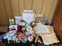 Overview photo showing the full assortment of craft supplies including threads, ribbons, elastic, bows, embroidery sampler kit, fabric glue, lace fabric pieces, and sewing accessories.