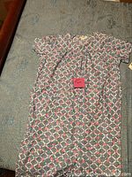 Full view of the dress laid flat showing the multicolor geometric and floral pattern and short sleeve design.