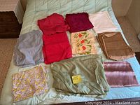 Various fabric pieces in different sizes and colors laid on a bed, including solid colors and floral prints.