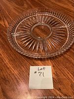 Clear glass divided serving dish with multiple wedge-shaped sections around a central circular section, starburst pattern radiating from the center, raised diamond edge pattern, shown on wood surface with lot number.