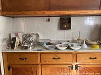 Assorted plates, bowls, metal chopper, gravy boat, hand mixer displayed on countertop