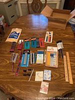 Full lot overview showing pens, pencils, ruler, clips, erasers, and address books laid out on wooden table