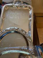 Silver plated serving trays and plates stacked and overlapping showing decorative edges and handles