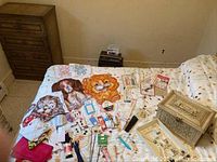 Sewing box, assorted fabric pieces with animal prints, assorted sewing cards with needles, pins, and buttons spread out on bed.