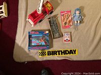 Photo showing all six items including Fisher-Price fire truck, navy ship model, Barbie jewelry package, small doll, jumbo cards, and laser toy.