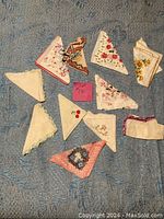 Top view of 11 women's handkerchiefs displayed on blue fabric background, showing summer themed floral prints and decorative borders in multiple colors and styles.