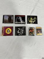Photo showing 7 music items: 5 CDs and 2 cassette tapes by Alice Cooper, arranged in 2 rows.
