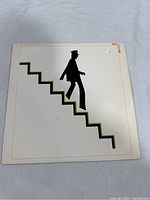 Front cover of Linton Kwesi Johnson's Bass Culture vinyl record showing minimalistic art of a silhouette man walking down stairs.