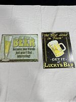 Both beer signs shown side by side on white cloth background.