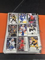 Page of 9 hockey cards in clear sleeves, featuring players from various NHL teams