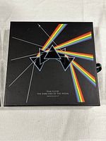 Closed black collector's box featuring prism and rainbow light spectrum album cover with the text 'Pink Floyd The Dark Side of the Moon Immersion Box Set'.