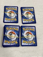 Four stacks of Pokemon cards with blue backs held together by rubber bands.