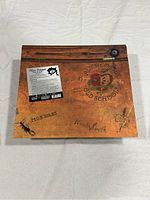 Top view of original album box showing artistic brown-orange textured box with 'Alice Cooper School's Out' text, a rose graphic, and additional design elements.
