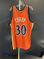 Back view of the orange Stephen Curry jersey showing the name "CURRY" and number 30 in large navy and white lettering.