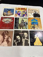 Nine vinyl records laid out in three rows showing all covers clearly, diverse collection including various artists and soundtracks