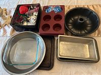 Photo showing various silicone and metal baking pans with glass Pyrex dishes and tin container with cookie cutters