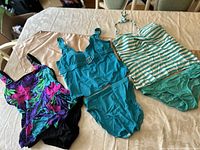Three bathing suits displayed flat on a table, showing different colors and styles.
