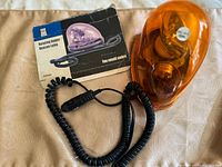 Rotating amber beacon light with amber dome, black base, coiled car power cord, and original box.