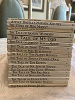 Stack of 18 children's books by Beatrix Potter and similar authors, showing spines with titles and volume numbers
