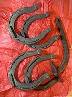 Four large rusted metal horseshoes on red background.