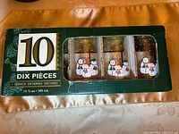 Original green box with 10 clear tall glasses decorated with Christmas caroling snowmen, visible through window.