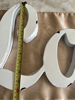 White metal 'Love' sign showing length measurement of about 28.5 inches with visible black paint wear marks.
