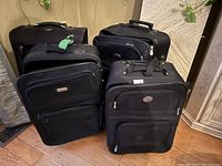 Four black carry-on luggage bags arranged together, showing overall condition and design