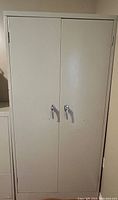 Closed tall metal cabinet showing double doors and metal handles.
