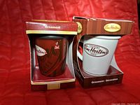 Front view of the two Tim Hortons mug ornaments in their boxes showing the brown and white mugs.
