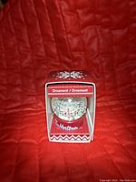 Front view of Tim Hortons snow globe ornament in original box displaying the snow globe with red base and Tim Hortons logo inside a decorated red box.