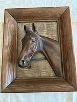 Full view of vintage horse head relief mounted on wood frame with mesh background and hanging chain.