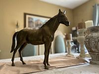 Front and side view of brass horse on table with background of room decor to show size and detail.