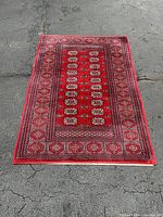Full view of red Bokhara pattern area rug laid on pavement