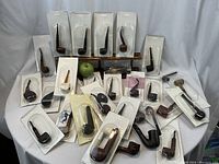 Wide shot of 29 blister-packaged pipes arranged around a wooden stand with a green apple for scale