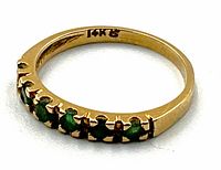 Close-up angled view showing prong-set green gemstones and inner 14K hallmark