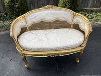 Front view of caned settee showing carved crest and seat cushion