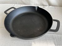 Top view of the Food Network cast iron skillet showing two handles and two pour spouts. The cooking surface is stained.