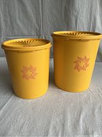 Front view of two orange-yellow vintage Tupperware canisters showing floral decals.